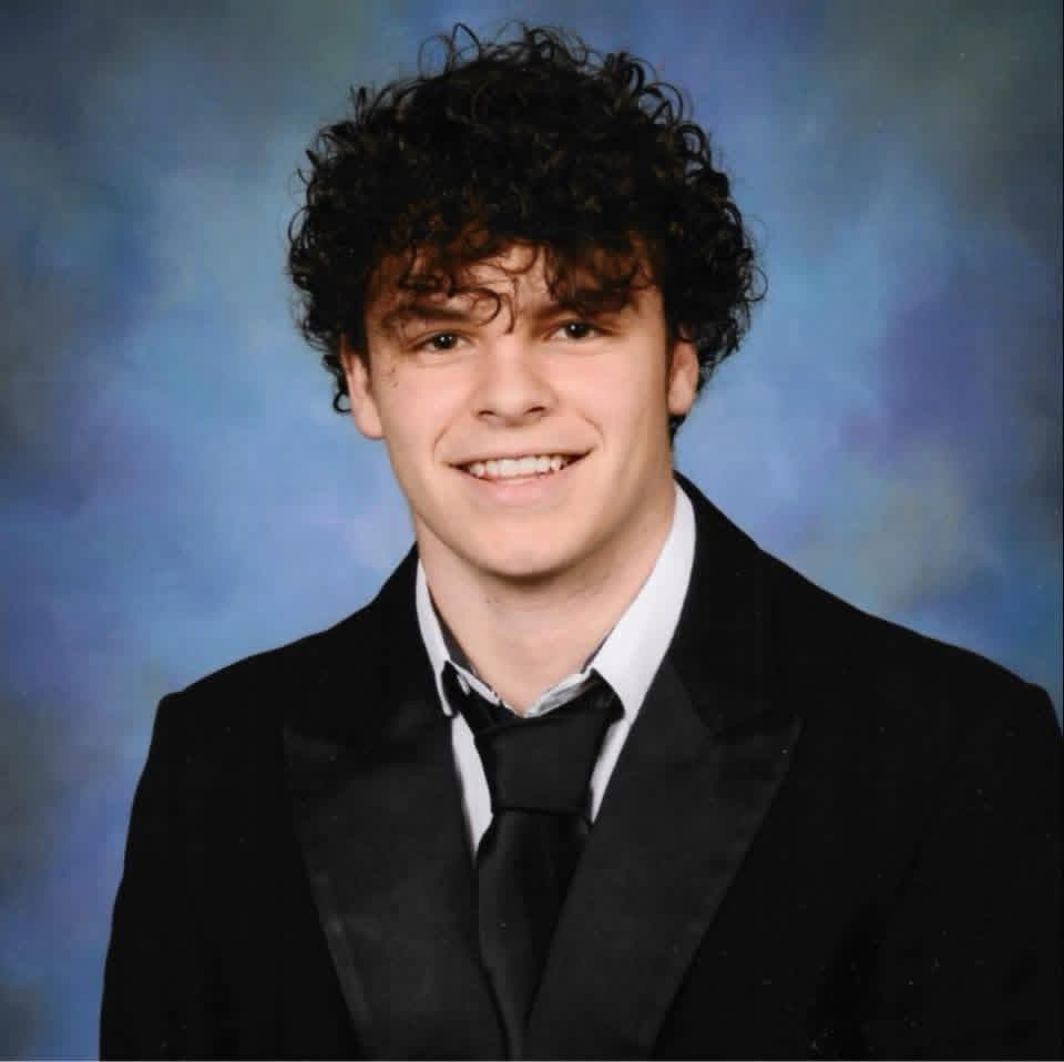 Drake Moyer, smiling, in a black suit and tie